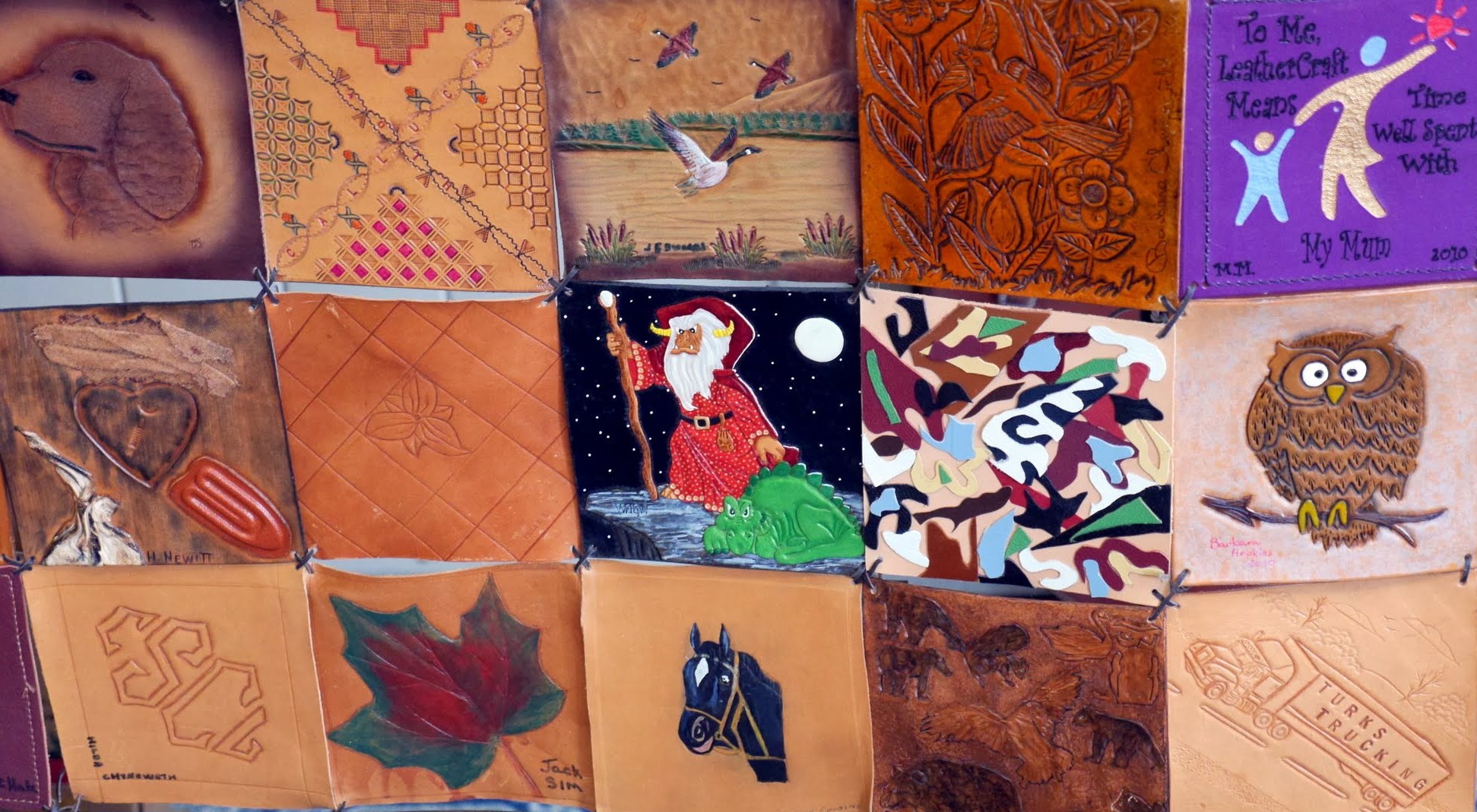 Fifteen squares of the Society&rsquo;s leather quilt, laced together with thongs &mdash; a dog&rsquo;s head, cross-stitch and basketweave, geese over a marsh, a tooled cardinal among flowers, a purple square reading &lsquo;To Me, LeatherCraft Means Time Well Spent With My Mum&rsquo;, a wizard and a dragon, a mosaic of coloured inlays, an owl on a branch, the Society&rsquo;s monogram, a maple leaf, a horse&rsquo;s head, animals of the bush, and a truck lettered Turks Trucking
