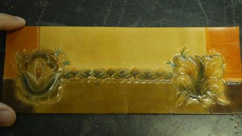 A panel with a tooled rose and leaf, partly coloured