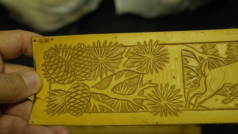 A carved panel with pine cones and a deer