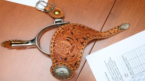 A carved spur strap with a silver concho