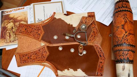 A carved vest with cowhide panels, with spurs and a carved cuff