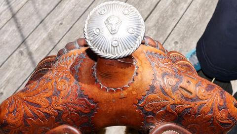 A silver concho on the saddle