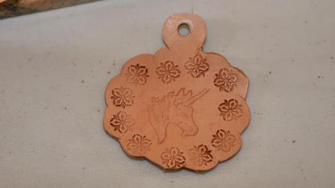A stamped luggage tag with a unicorn and flowers