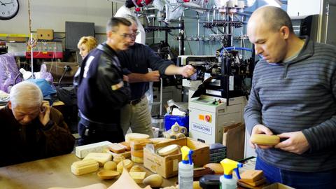 A man examines a wooden box form while members talk at a table of forms and supplies