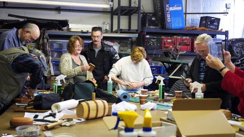 Members work around a long table covered with box forms, tools and supplies at the lasting workshop