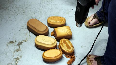 Several leather-covered box forms of different shapes on the floor as a heat gun dries them