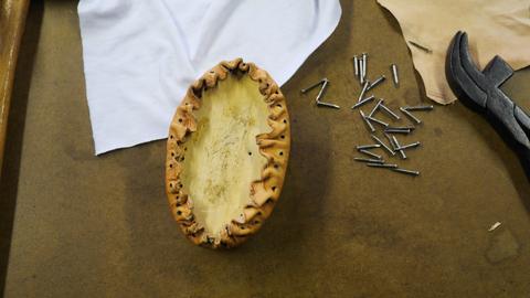 Gathered leather tacked around an oval form next to loose tacks and lasting pliers