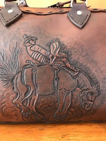 A carved bronc rider on the bag